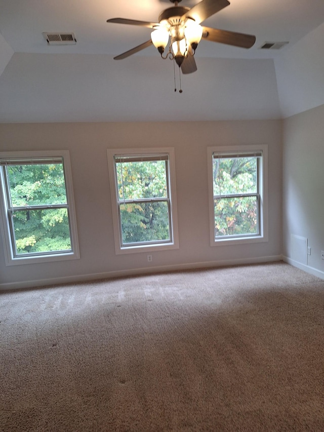 spare room featuring vaulted ceiling, carpet flooring, visible vents, and baseboards