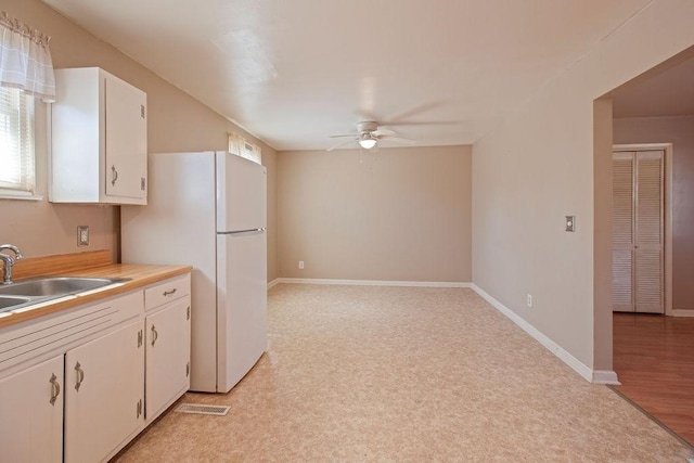 kitchen with a ceiling fan, light countertops, white cabinetry, and a sink