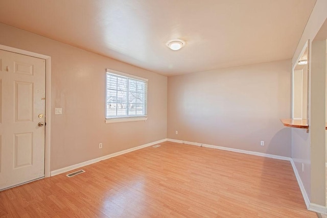 empty room with light wood-style flooring, visible vents, and baseboards