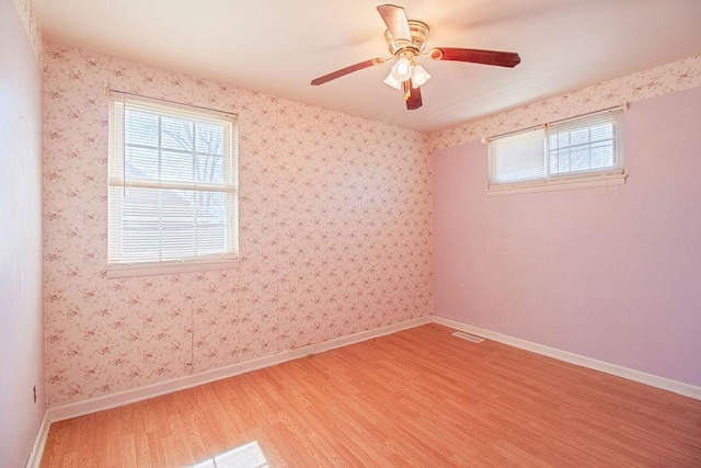 spare room with light wood-type flooring, visible vents, baseboards, and wallpapered walls