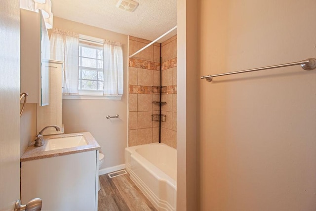 full bath featuring visible vents, a textured ceiling, toilet, and wood finished floors