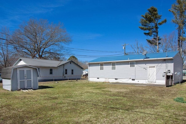 rear view of house with a storage shed, metal roof, an outbuilding, crawl space, and a yard