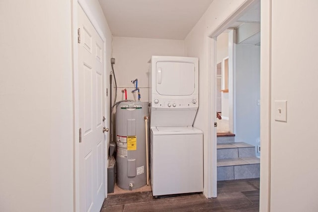 clothes washing area with water heater, dark wood-style flooring, and stacked washer and clothes dryer