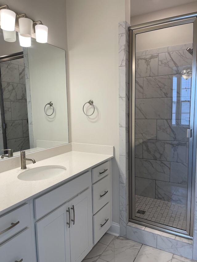 full bathroom featuring marble finish floor, a stall shower, and vanity