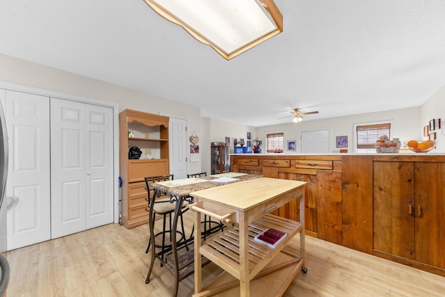 kitchen featuring brown cabinets, light countertops, ceiling fan, and light wood-style flooring