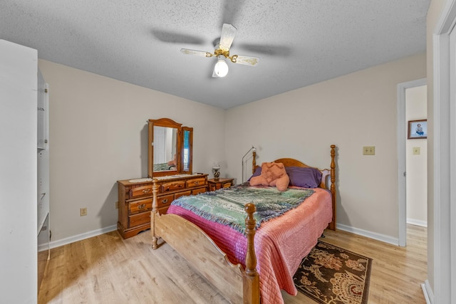 bedroom featuring light wood-style floors, a textured ceiling, and baseboards