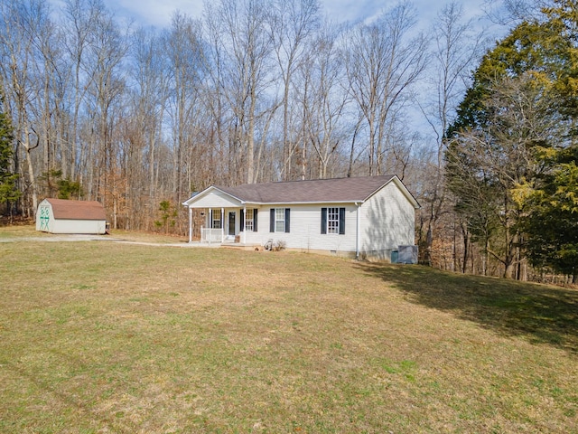 view of front of home featuring covered porch, a storage unit, a front lawn, and an outbuilding