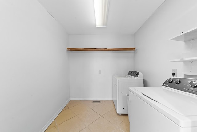 laundry room featuring laundry area, light tile patterned floors, baseboards, and washer and clothes dryer