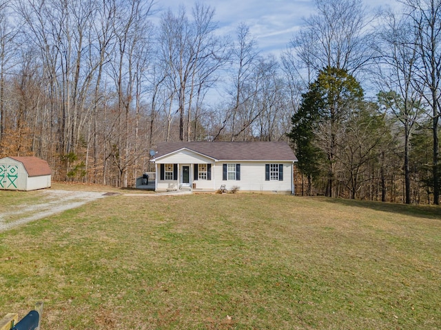 view of front of house with a front yard, an outdoor structure, driveway, and a storage unit