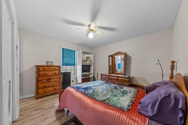 bedroom with a ceiling fan, light wood-style flooring, baseboards, and a textured ceiling