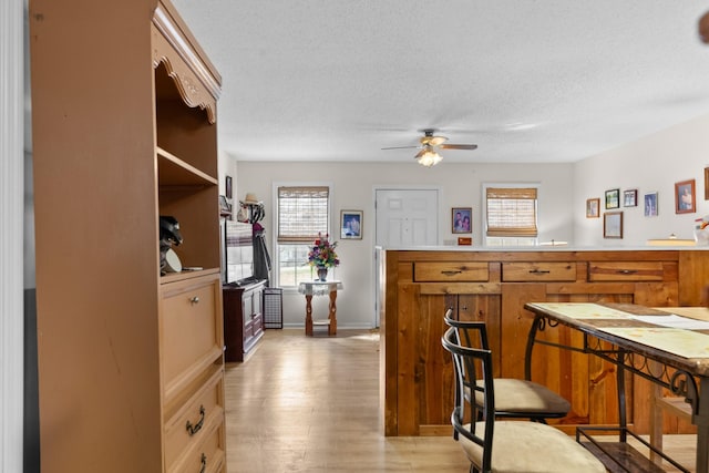 kitchen featuring a textured ceiling, ceiling fan, light wood-style floors, open shelves, and brown cabinetry