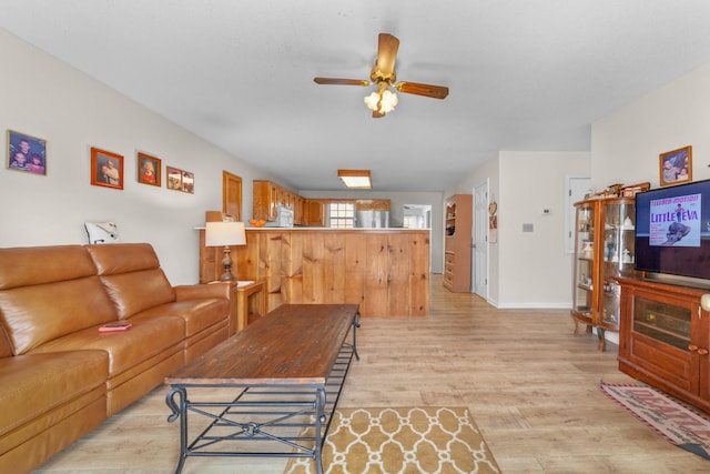 living room with light wood-style floors, baseboards, and a ceiling fan