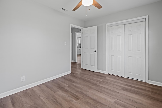 unfurnished bedroom with baseboards, visible vents, a ceiling fan, wood finished floors, and a closet