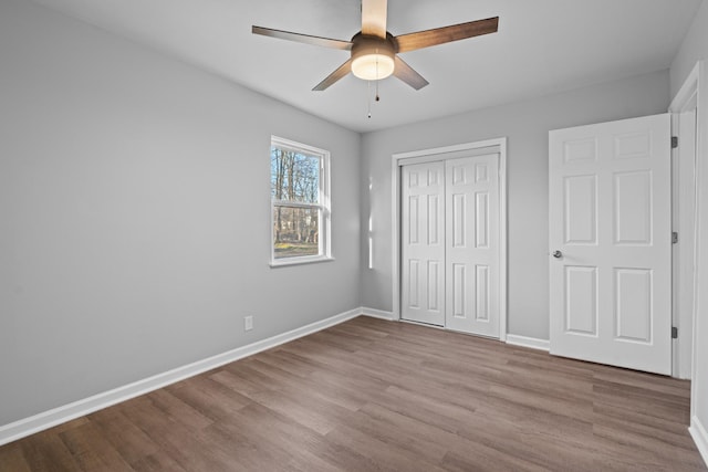 unfurnished bedroom featuring a closet, ceiling fan, baseboards, and wood finished floors