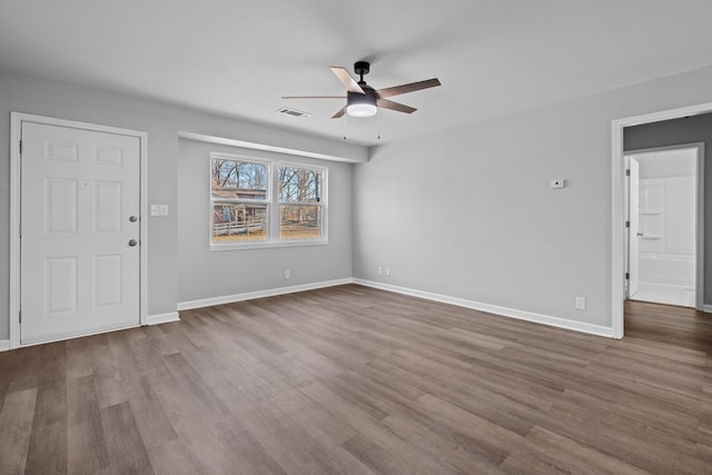 interior space featuring a ceiling fan, dark wood finished floors, visible vents, and baseboards