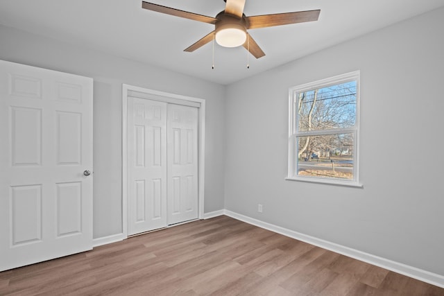 unfurnished bedroom with a closet, light wood-type flooring, a ceiling fan, and baseboards