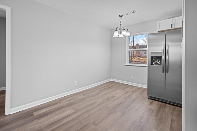 kitchen featuring baseboards, visible vents, stainless steel fridge with ice dispenser, wood finished floors, and white cabinetry