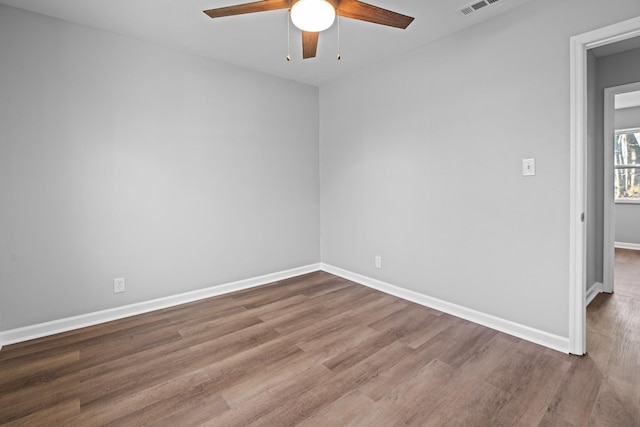 spare room featuring a ceiling fan, visible vents, baseboards, and wood finished floors