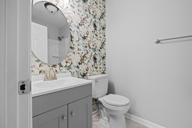 bathroom with toilet, wallpapered walls, baseboards, and vanity