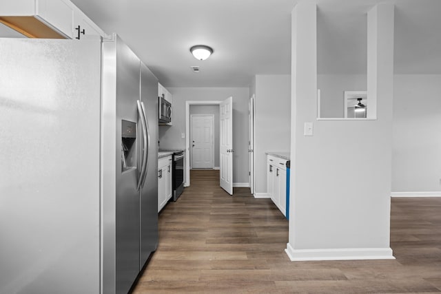 kitchen with appliances with stainless steel finishes, wood finished floors, and white cabinetry