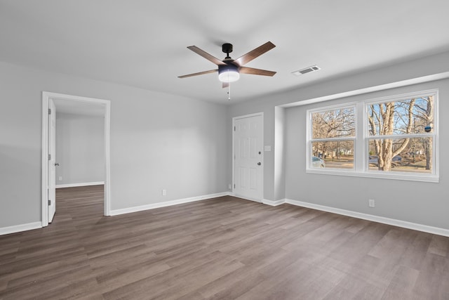 spare room with ceiling fan, dark wood-type flooring, visible vents, and baseboards