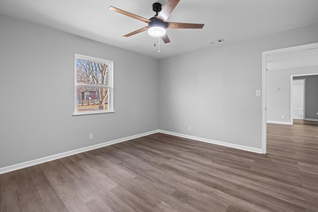 unfurnished room featuring dark wood-style floors, baseboards, visible vents, and a ceiling fan