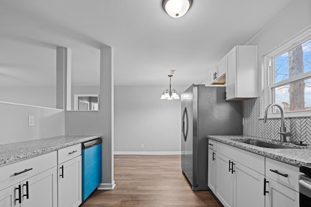 kitchen featuring dark wood finished floors, backsplash, appliances with stainless steel finishes, white cabinets, and a sink