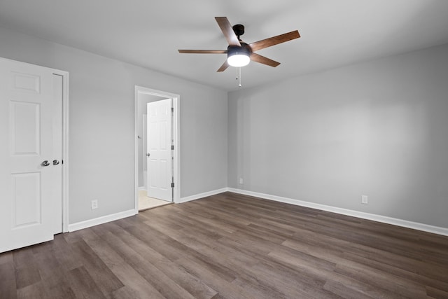 unfurnished bedroom featuring dark wood-style floors, ceiling fan, connected bathroom, and baseboards