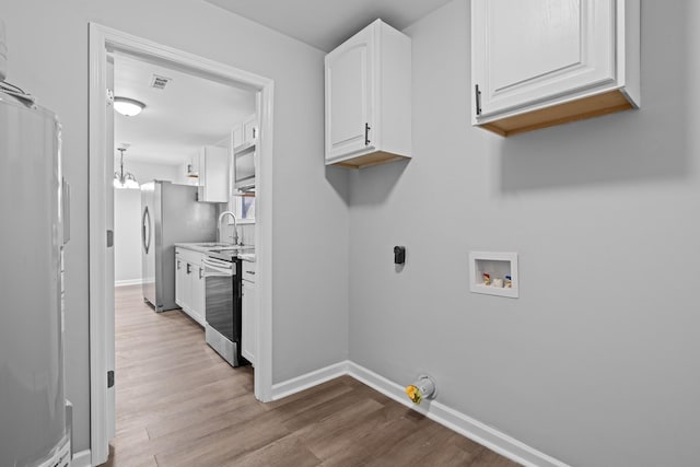 laundry room featuring hookup for a washing machine, visible vents, a sink, wood finished floors, and baseboards