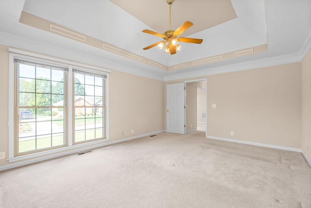 spare room with light colored carpet, visible vents, baseboards, a tray ceiling, and crown molding