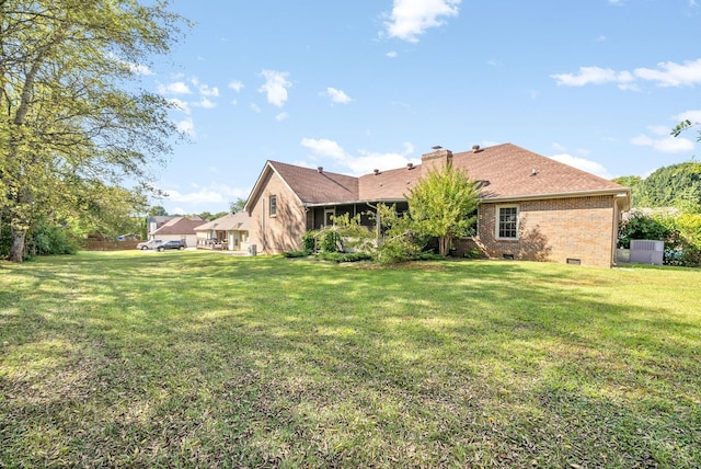 rear view of property featuring crawl space, brick siding, a lawn, and a chimney