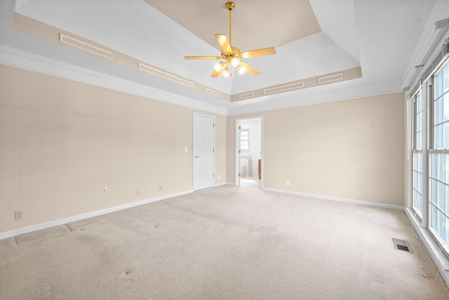 spare room featuring ornamental molding, a raised ceiling, light colored carpet, and baseboards