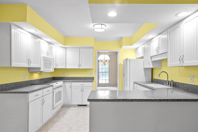 kitchen with light tile patterned floors, a peninsula, white appliances, a sink, and white cabinetry