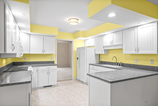 kitchen with white appliances, dark countertops, a peninsula, white cabinetry, and a sink