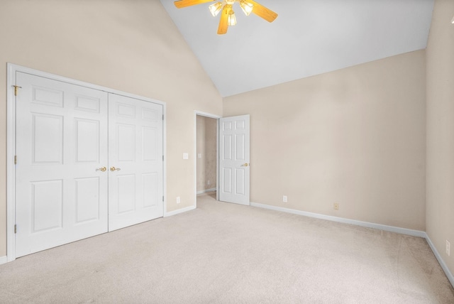 unfurnished bedroom featuring baseboards, high vaulted ceiling, a closet, and light colored carpet