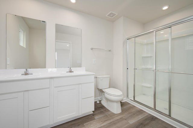 bathroom with vanity, wood finished floors, visible vents, a stall shower, and toilet