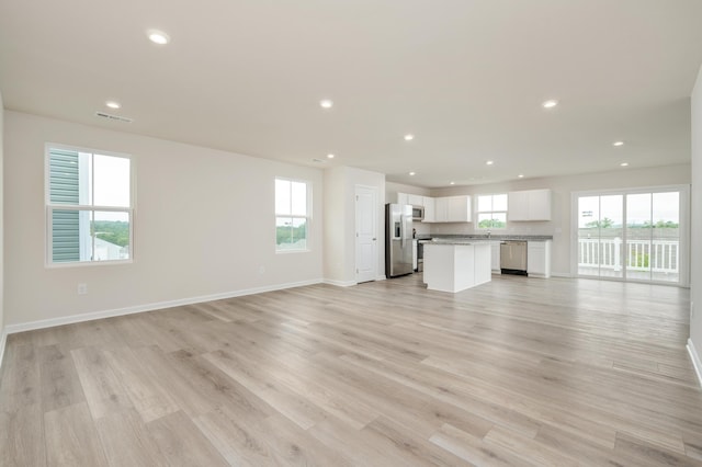 unfurnished living room featuring plenty of natural light, recessed lighting, baseboards, and light wood-style floors