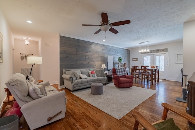 living area with a textured ceiling, an accent wall, wood finished floors, and wooden walls