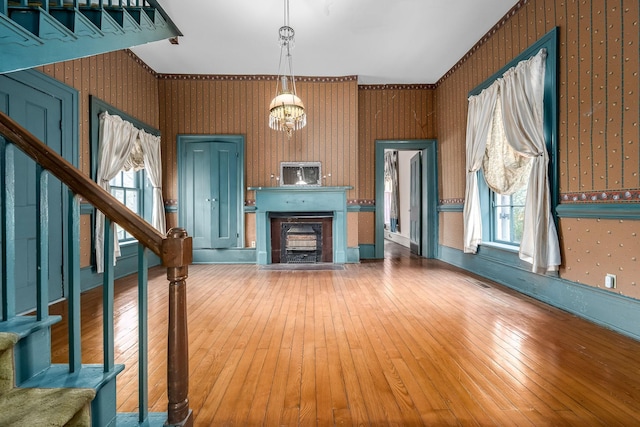 unfurnished living room with a wealth of natural light, hardwood / wood-style flooring, a fireplace, and stairs