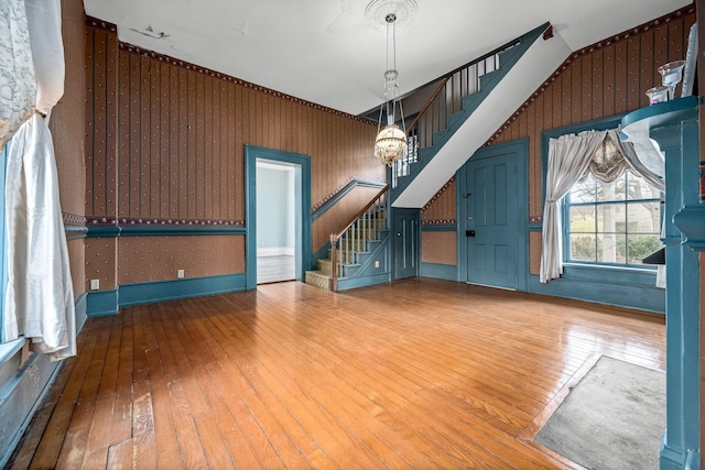 interior space with wood-type flooring, wallpapered walls, an inviting chandelier, and stairs