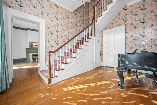 foyer with wallpapered walls, a fireplace, stairway, and hardwood / wood-style flooring