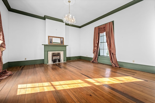 unfurnished living room with baseboards, hardwood / wood-style flooring, a fireplace with flush hearth, ornamental molding, and a notable chandelier