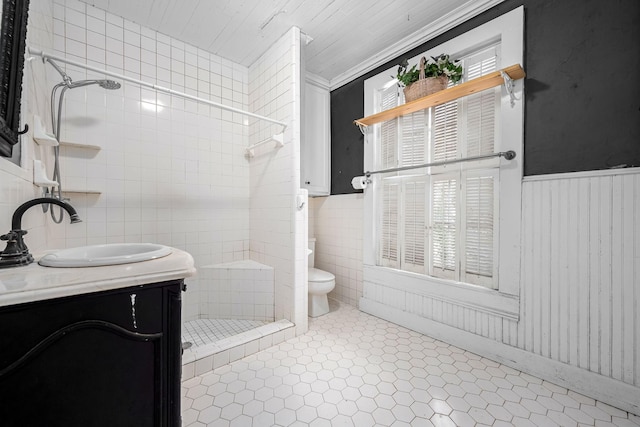 full bath featuring a stall shower, toilet, a wainscoted wall, tile patterned floors, and tile walls