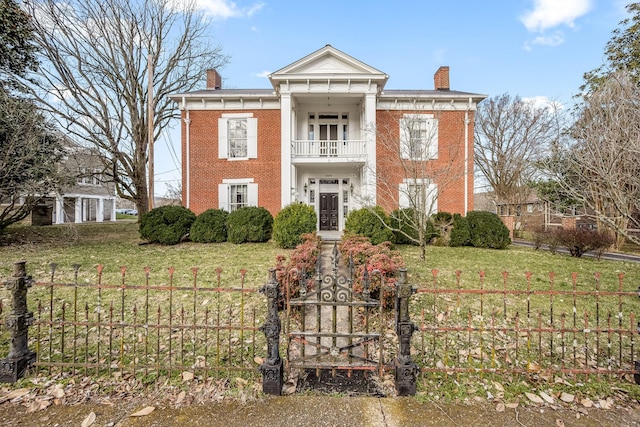 greek revival house featuring brick siding, a chimney, fence, and a balcony