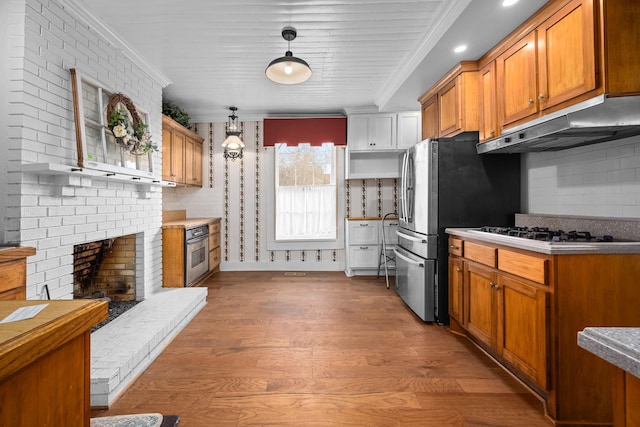 kitchen featuring brown cabinets, crown molding, gas cooktop, wood finished floors, and under cabinet range hood