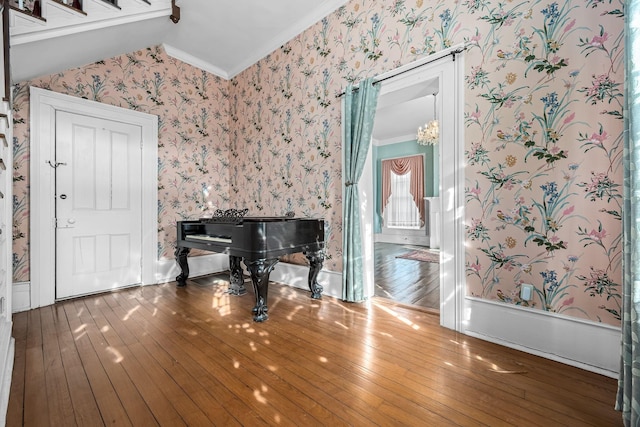 interior space featuring lofted ceiling, ornamental molding, hardwood / wood-style flooring, and wallpapered walls