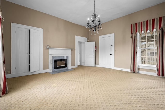 unfurnished living room with carpet floors, an inviting chandelier, baseboards, and a high end fireplace