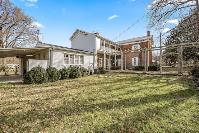 rear view of house featuring an attached carport, brick siding, and a lawn