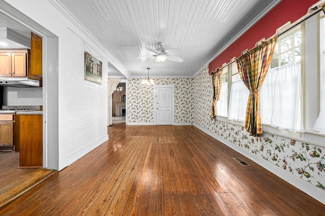 unfurnished room featuring wallpapered walls, visible vents, a ceiling fan, wood-type flooring, and crown molding