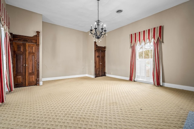 carpeted spare room featuring visible vents, a notable chandelier, and baseboards